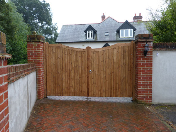 Curved-top timber gates across a paved driveway