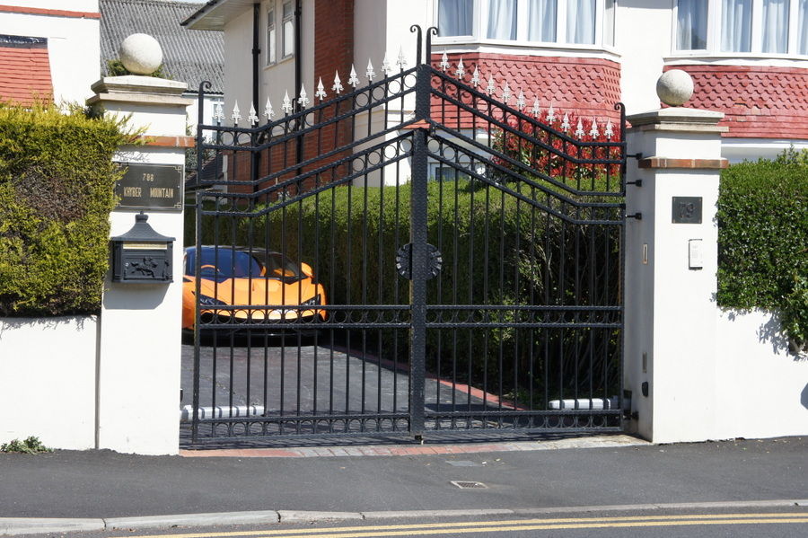 Black ornate metal swing gates between white piers