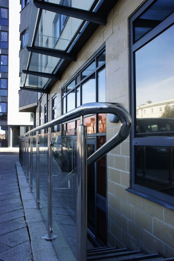 Stainless steel handrail with a curved end beside a building entrance