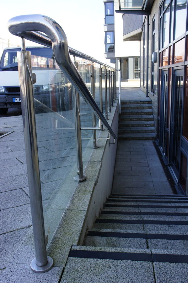 Stainless steel handrail with glass infill down steps to a lower entrance