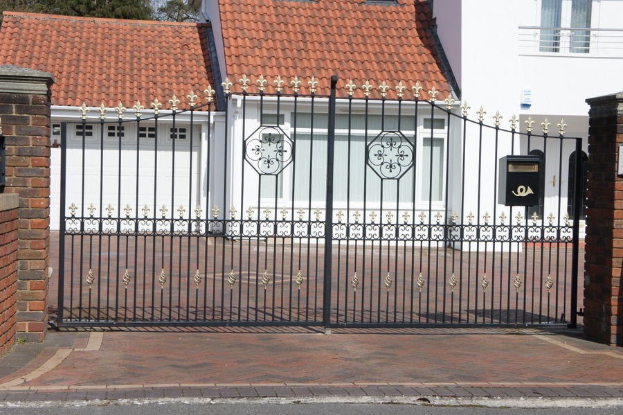 Black metal driveway gates with gold finials