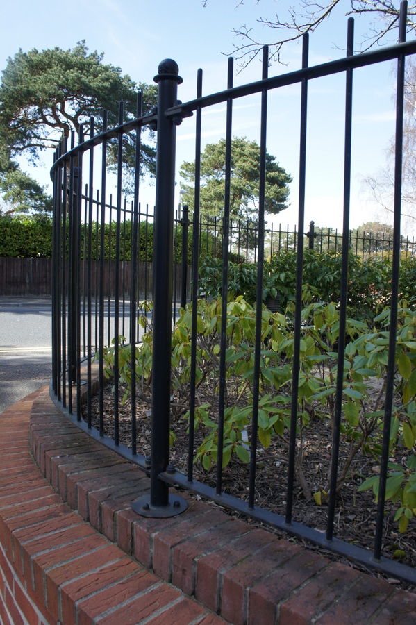 Black metal railings with a ball-top post following a curved wall