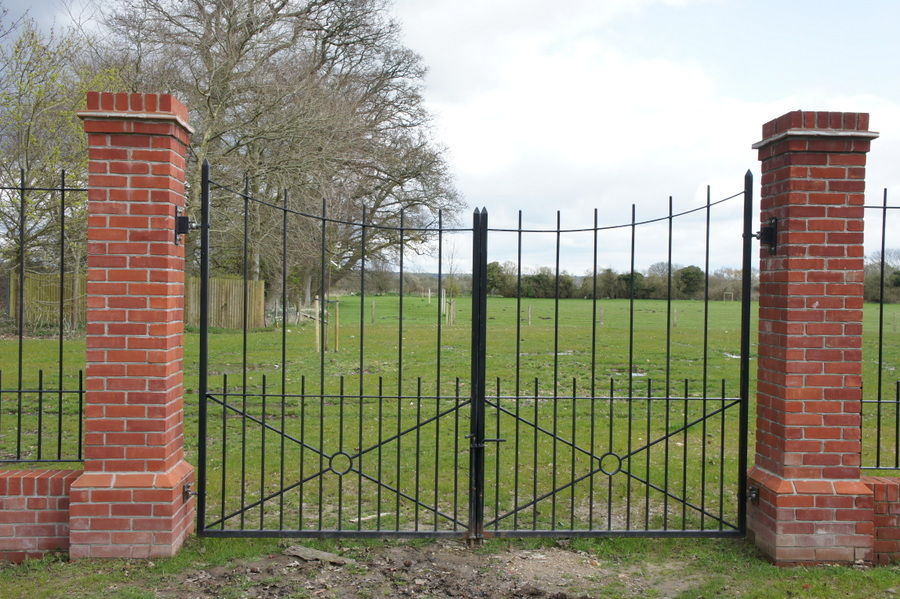 Black metal double gates between tall brick piers