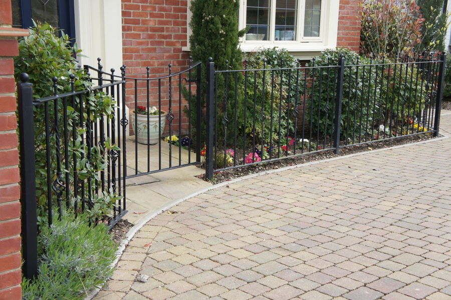 Low black railings and a small curved gate around a front garden