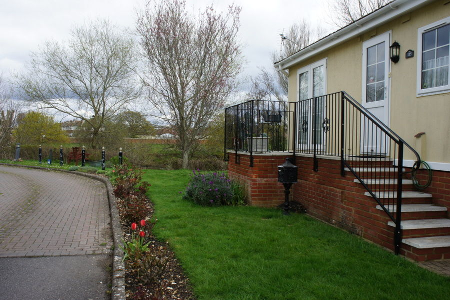 Black handrail following steps up to a raised entrance with a curled end