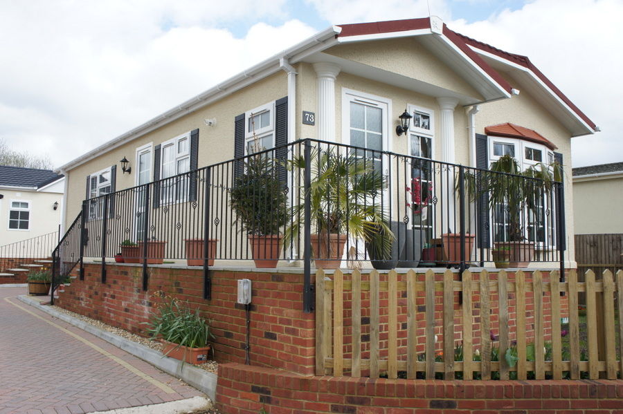 Black rails and a stepped handrail along the raised front of a park home