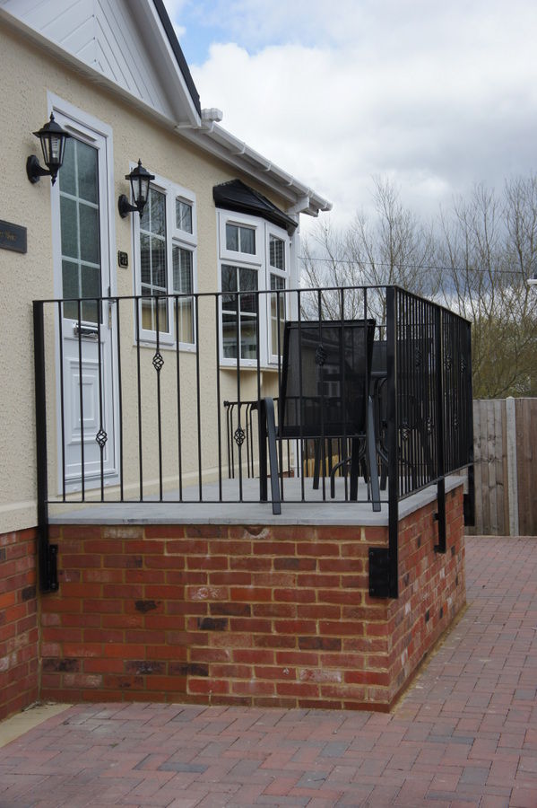 Raised balcony with black railings beside a park home