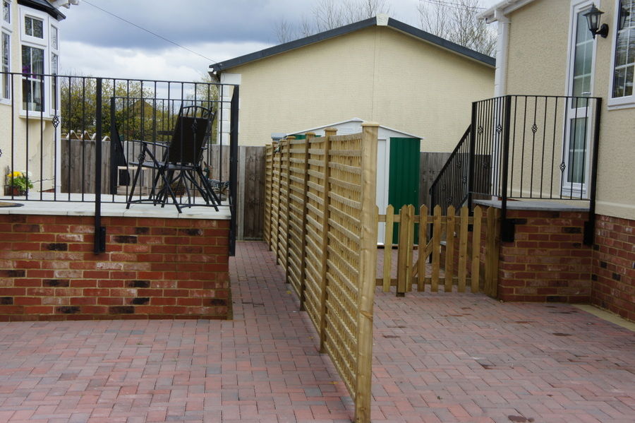 Black handrails on short steps and a raised platform beside a park home