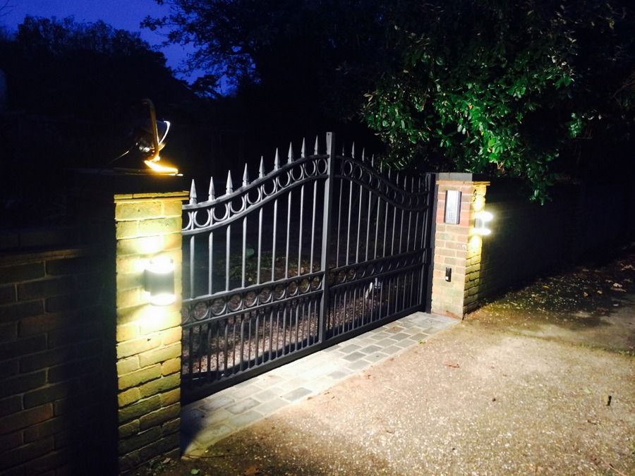 Automatic metal gates between lit brick piers at night