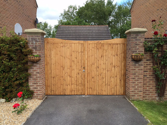 Timber double gates across a driveway between brick piers