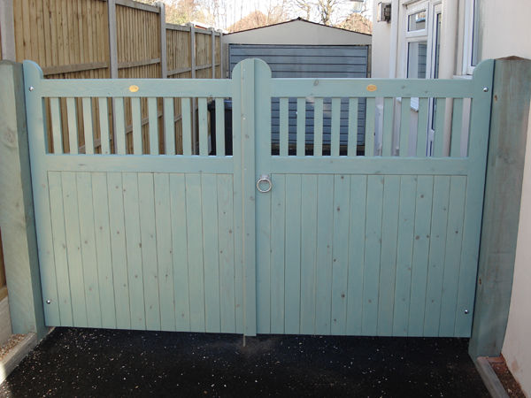 Wooden double gates painted sage green with open spindles along the top