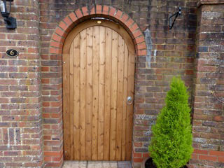 Arched timber pedestrian gate set into a brick archway