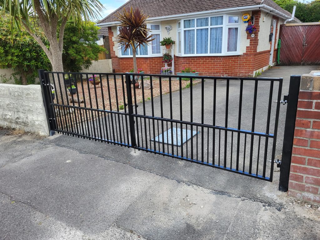 Plain black flat-top metal double gates across a bungalow driveway