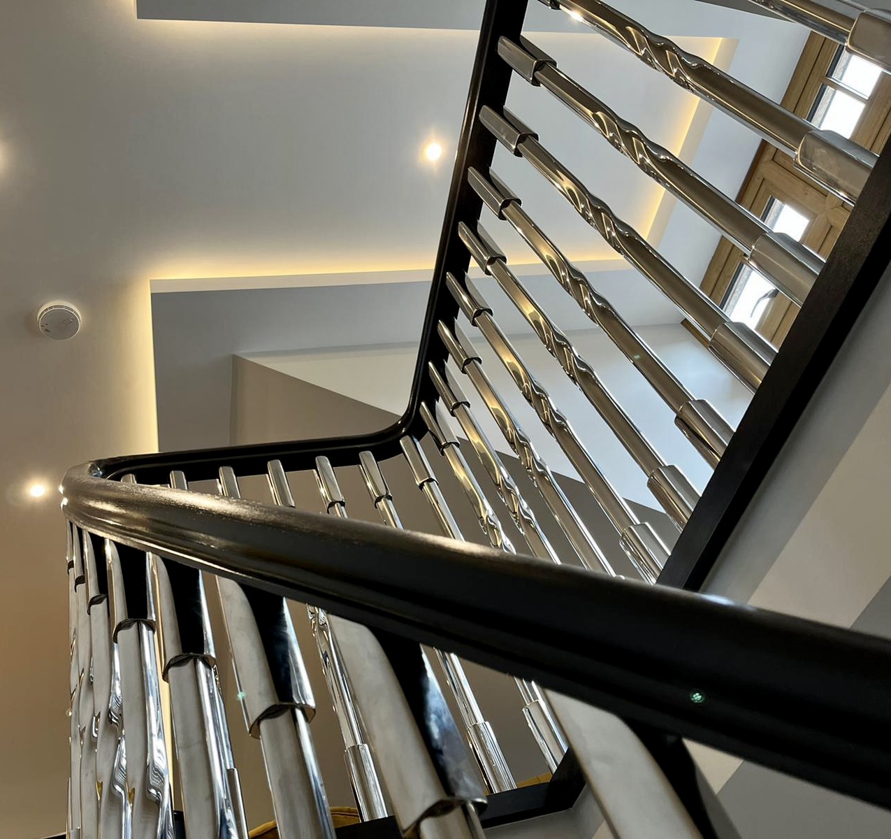 Black handrail on an internal staircase with twisted stainless steel balusters